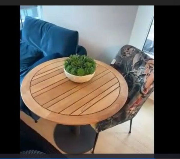 1. Round wood Reperch side table with slatted top, paired with a chair and a sofa, plant decor on top.  