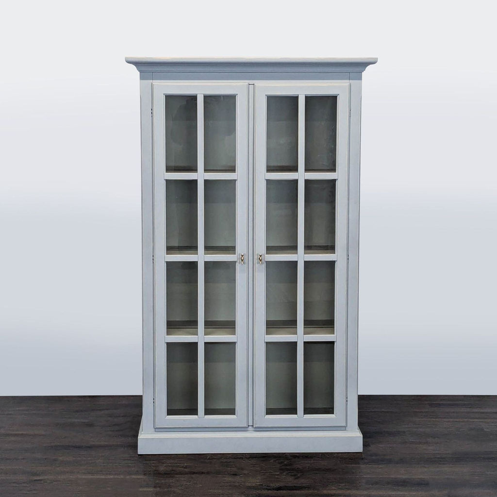 Modern Crate & Barrel bookshelf with glass double doors, soft gray finish, and four adjustable shelves.