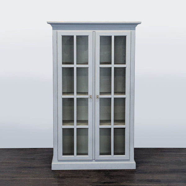 Modern Crate & Barrel bookshelf with glass double doors, soft gray finish, and four adjustable shelves.