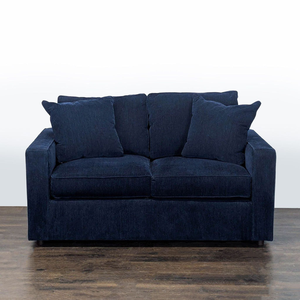 Navy blue Room and Board loveseat with modern design, thick cushions, and two matching pillows.