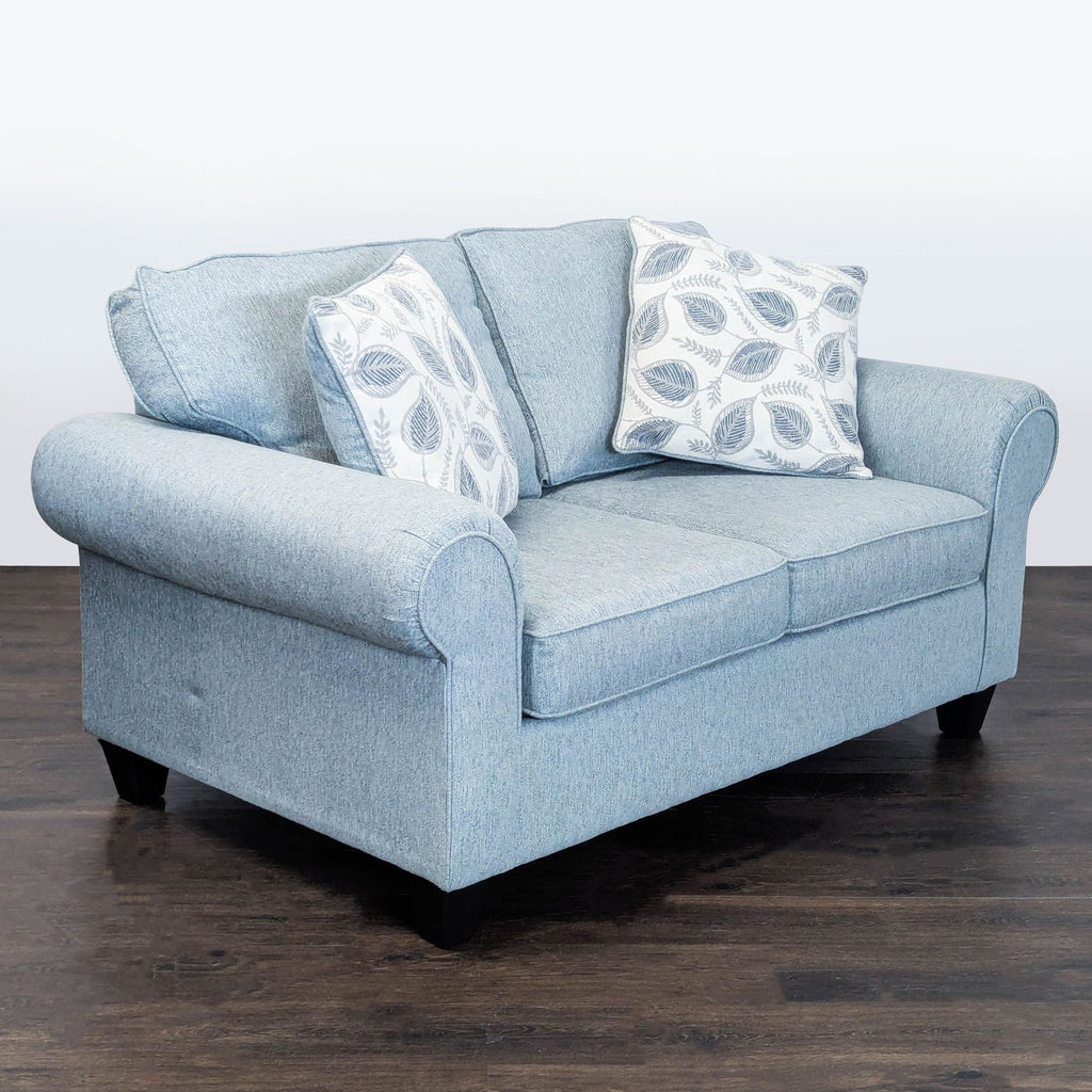Minhaus Furniture loveseat in soft blue fabric, featuring plush cushions, decorative leaf pillows, and sturdy legs.