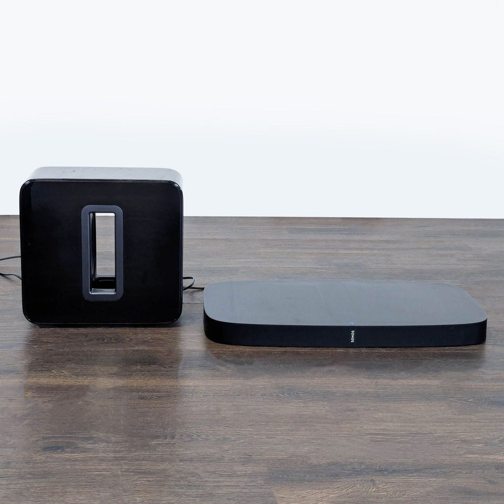 Black Sonos audio equipment set with subwoofer and playbase, designed for living room entertainment.  