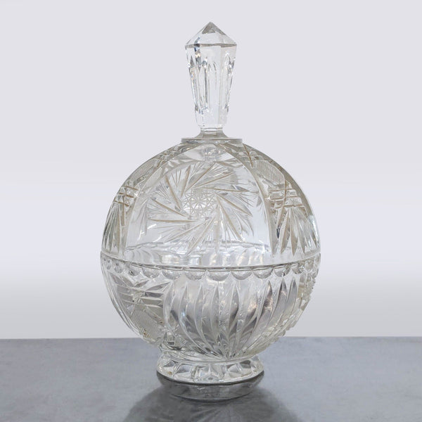 Vintage cut glass crystal bowl with lid on pedestal base, displaying elegant patterns; ideal for serving treats.