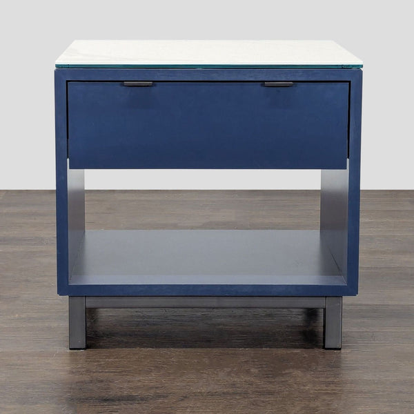 Navy end table with one drawer, open shelf, marbled white ceramic top, and black hardware by Room & Board.  