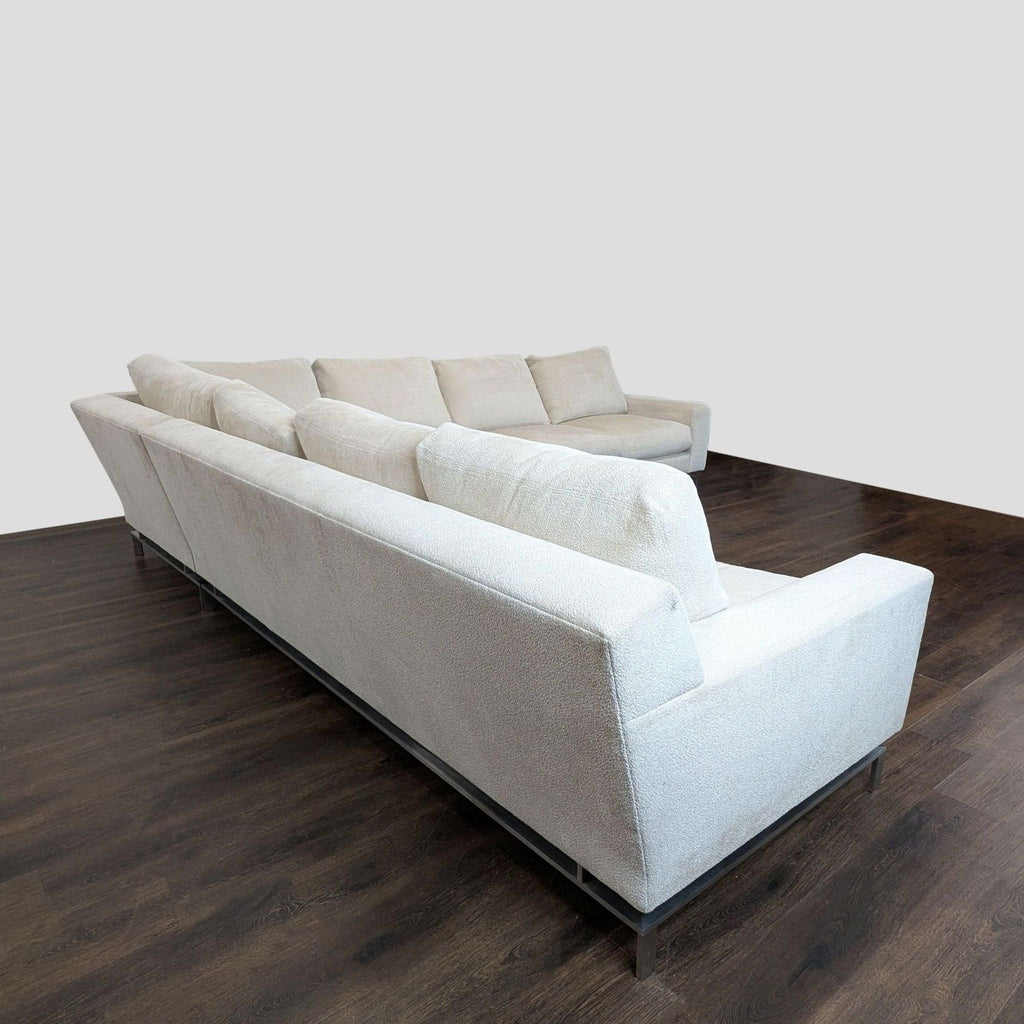 A. Rudin sectional sofa in light beige fabric, featuring a clean L-shape and sleek metal legs for versatile modern living rooms.