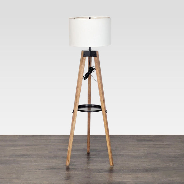 Pottery Barn tripod floor lamp with wooden base, built-in shelf, and classic white drum shade for soft lighting.  