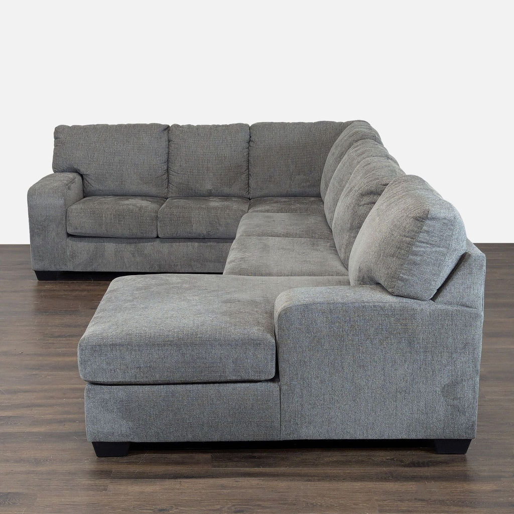 Gray Ashley sectional sofa with chaise, featuring soft cushions and sturdy construction for living rooms.  