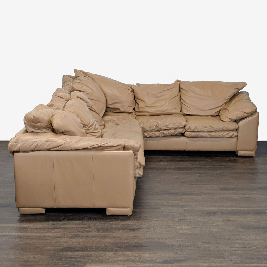 Spacious sectional in neutral tan leather, offering comfort and style; features soft cushions and minor wear.