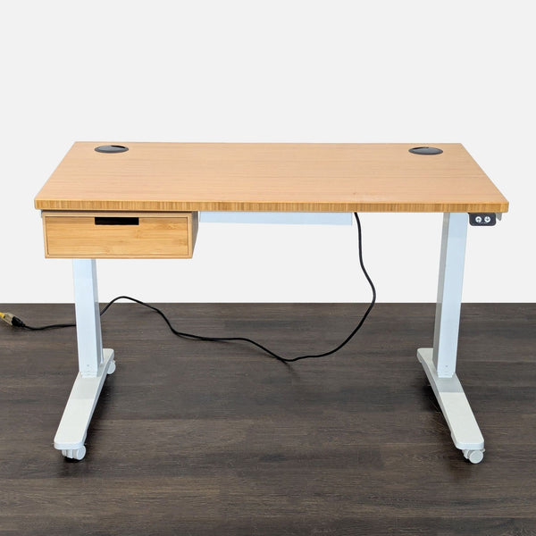 Uplift electric standing desk with bamboo top, white frame, built-in drawer, grommets, and lockable casters.
