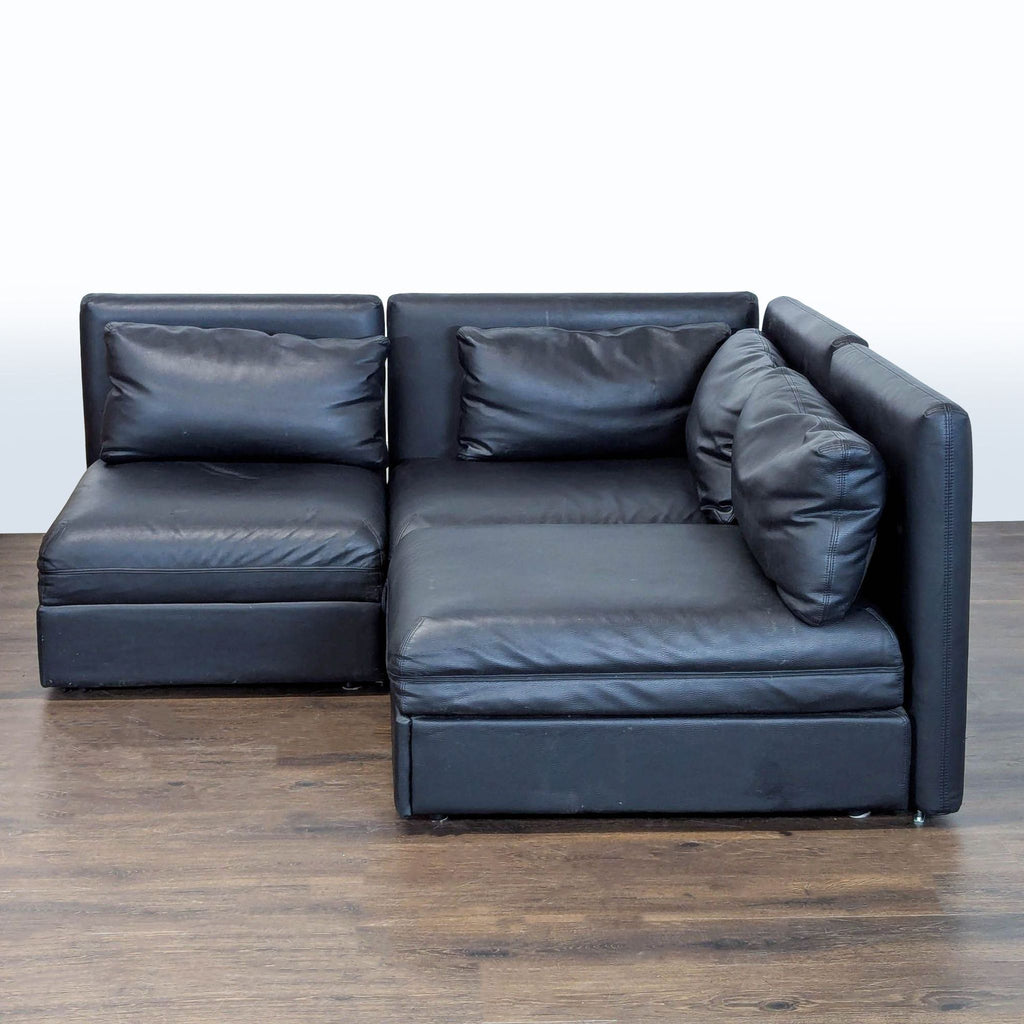 Black faux leather L-shaped sectional with storage chaise and pull-out sleeper, ideal for small living rooms.  
