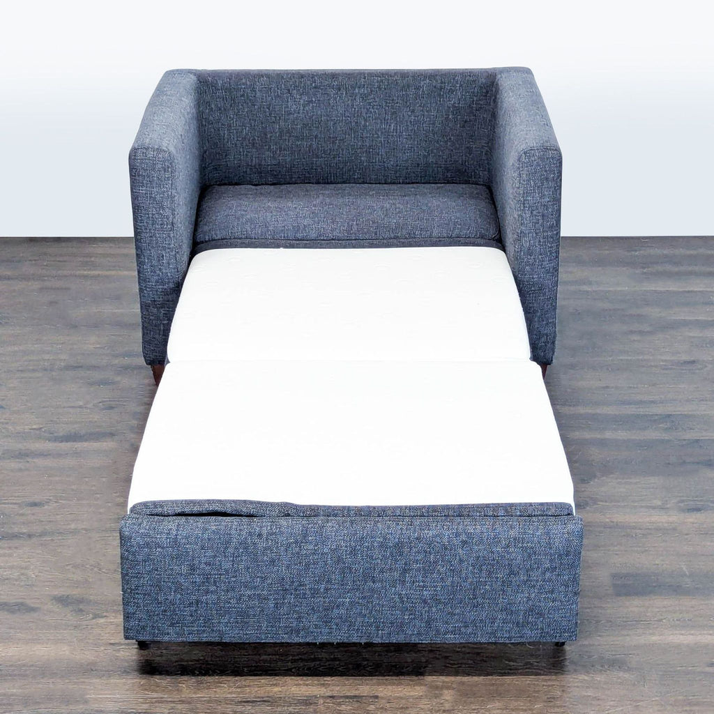 Sleek Living Spaces armchair in dark gray fabric, doubles as a pull-out sleeper for small rooms.
