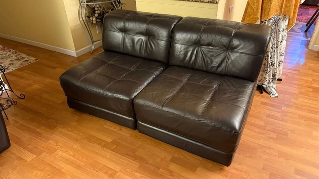 3. Chateau d’Ax sectional piece: two-seater brown leather sofa with tufted design, placed on a wooden floor.