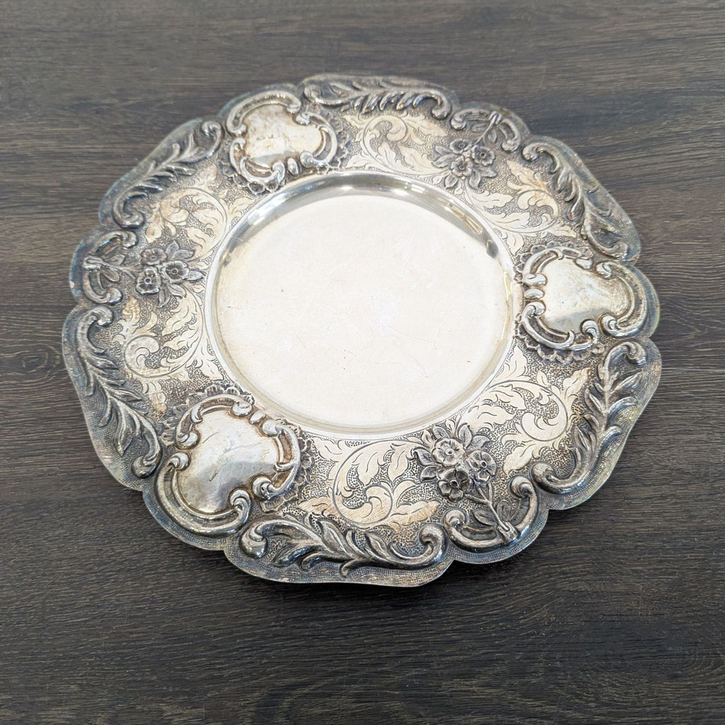 Vintage silver dish with ornate floral and scrollwork edge, featuring a classic antique style and natural patina.