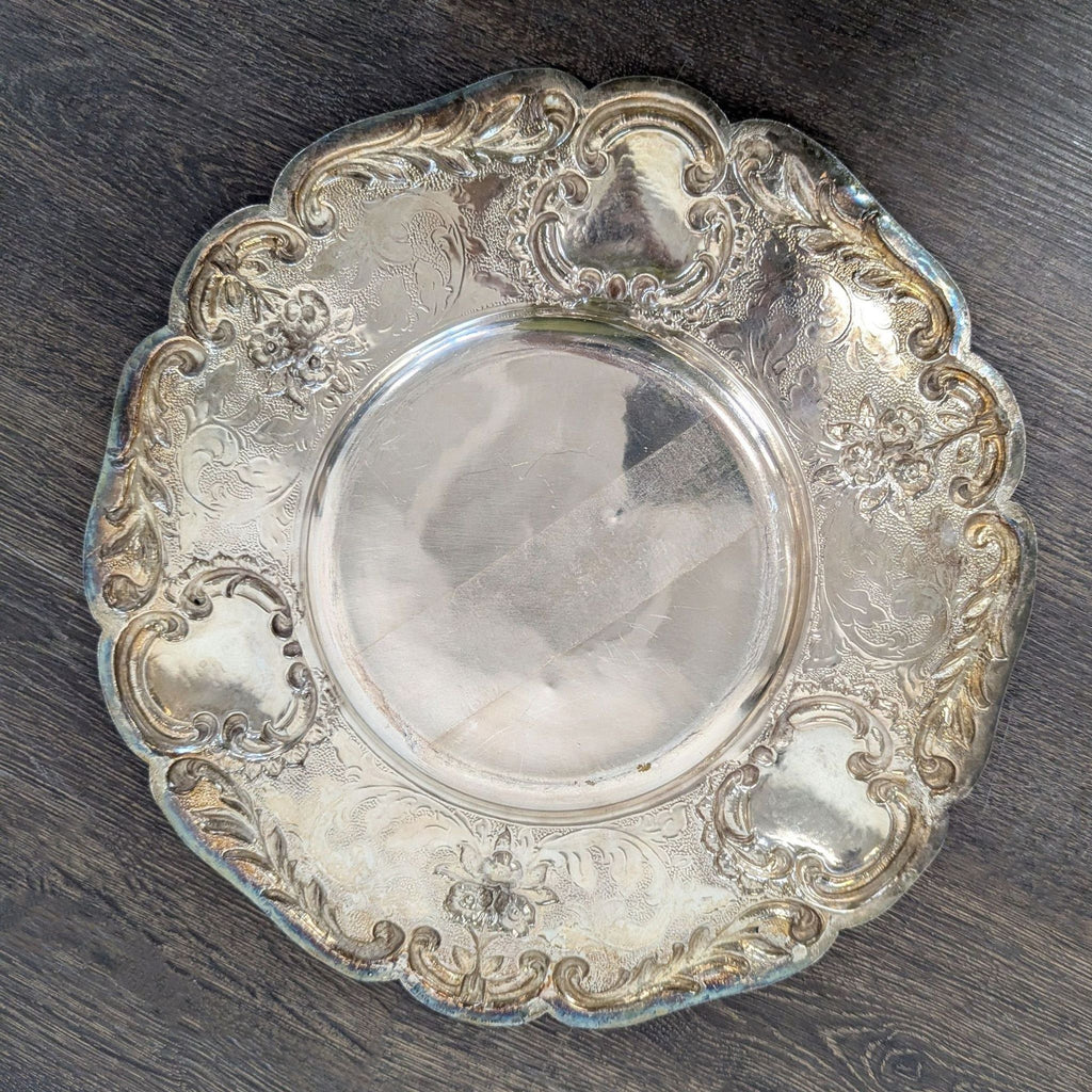 Elegant vintage dishware piece with intricate floral borders and visible patina, perfect for serving or display.