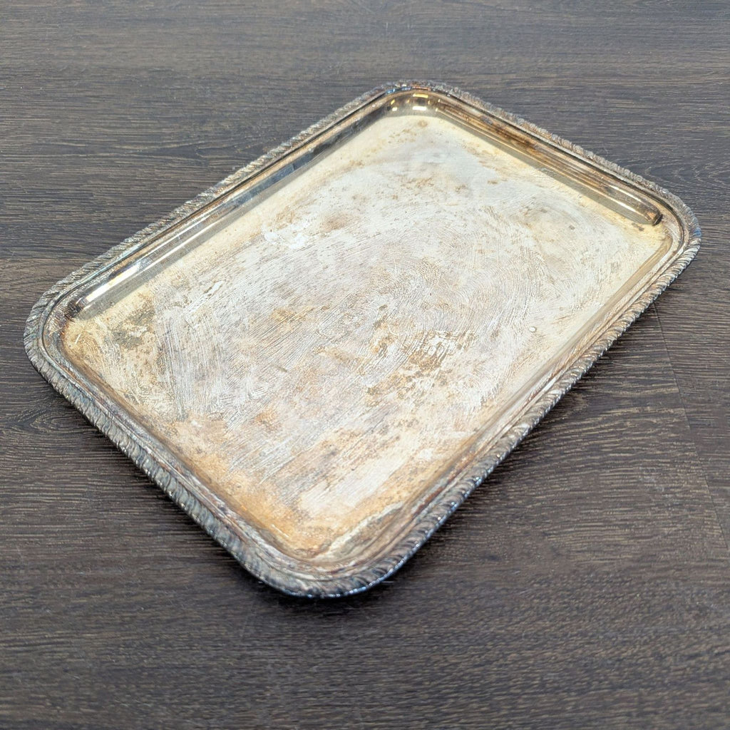 Vintage silver-plated tray featuring ornate edges, surface wear, and natural tarnish; ideal for serving or display.