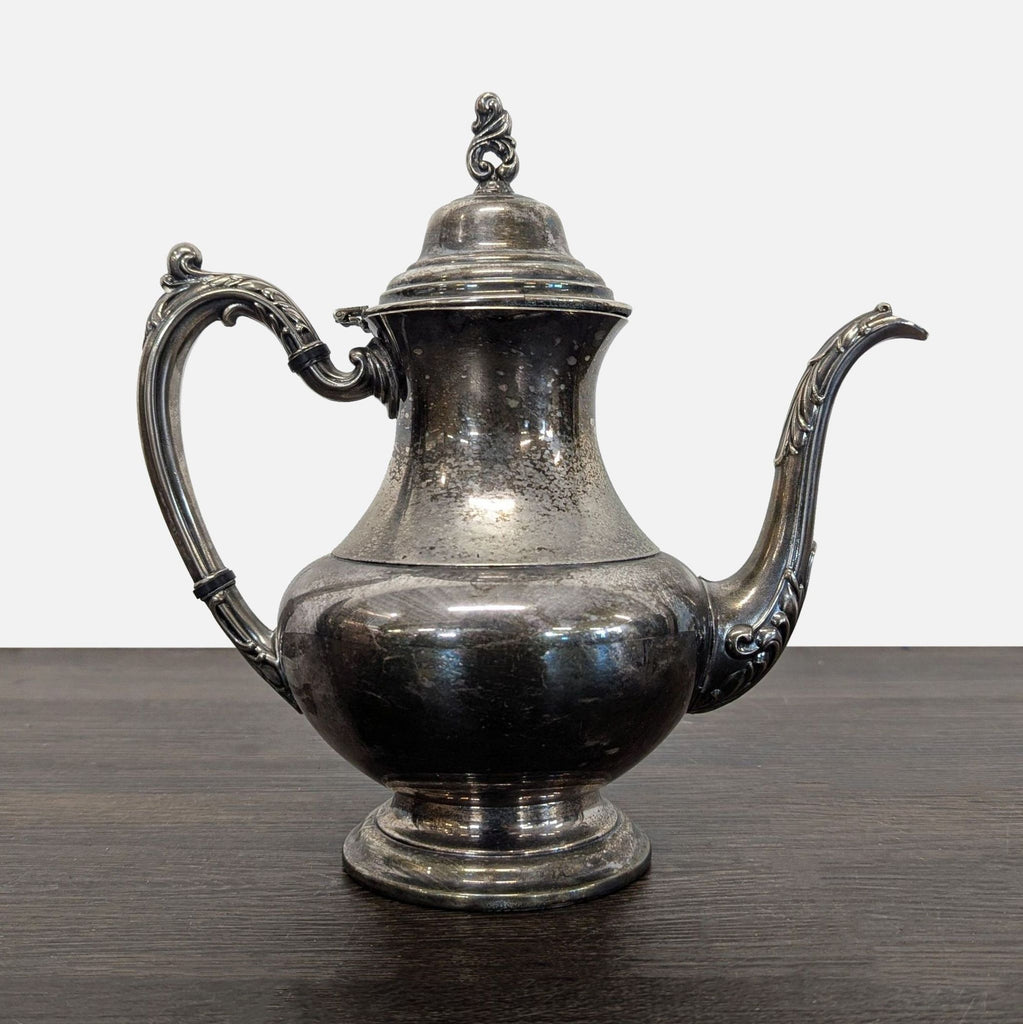 Vintage silver-plated teapot with ornate handle, spout, and a hinged lid, showing elegant patina from age.  