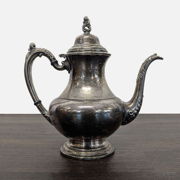 Vintage silver-plated teapot with ornate handle, spout, and a hinged lid, showing elegant patina from age.  
