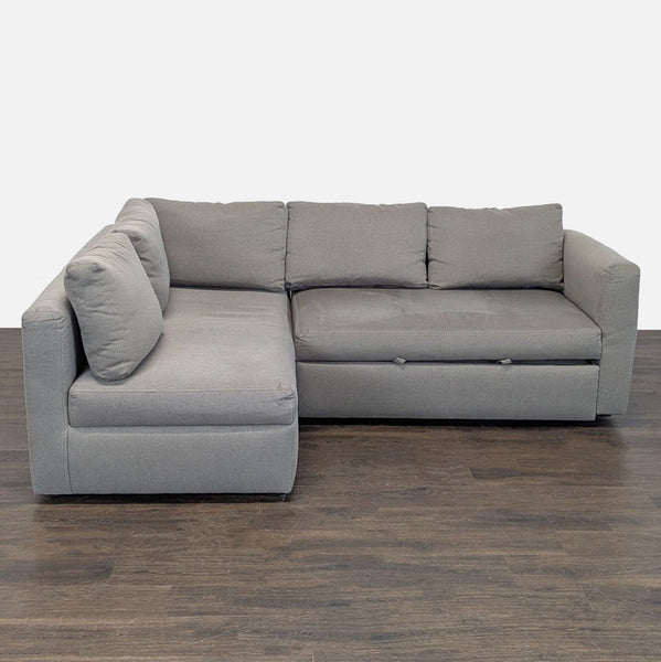 Modern gray Room & Board sectional with deep seating and a pull-out sleeper, perfect for guest accommodation.
