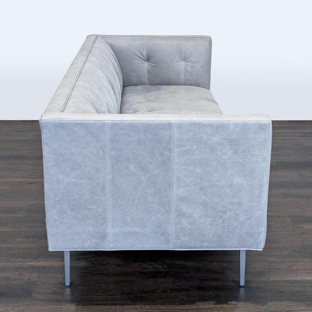 Contemporary Room & Board sofa with gray leather upholstery, tufted detailing, and minimalist metal legs.