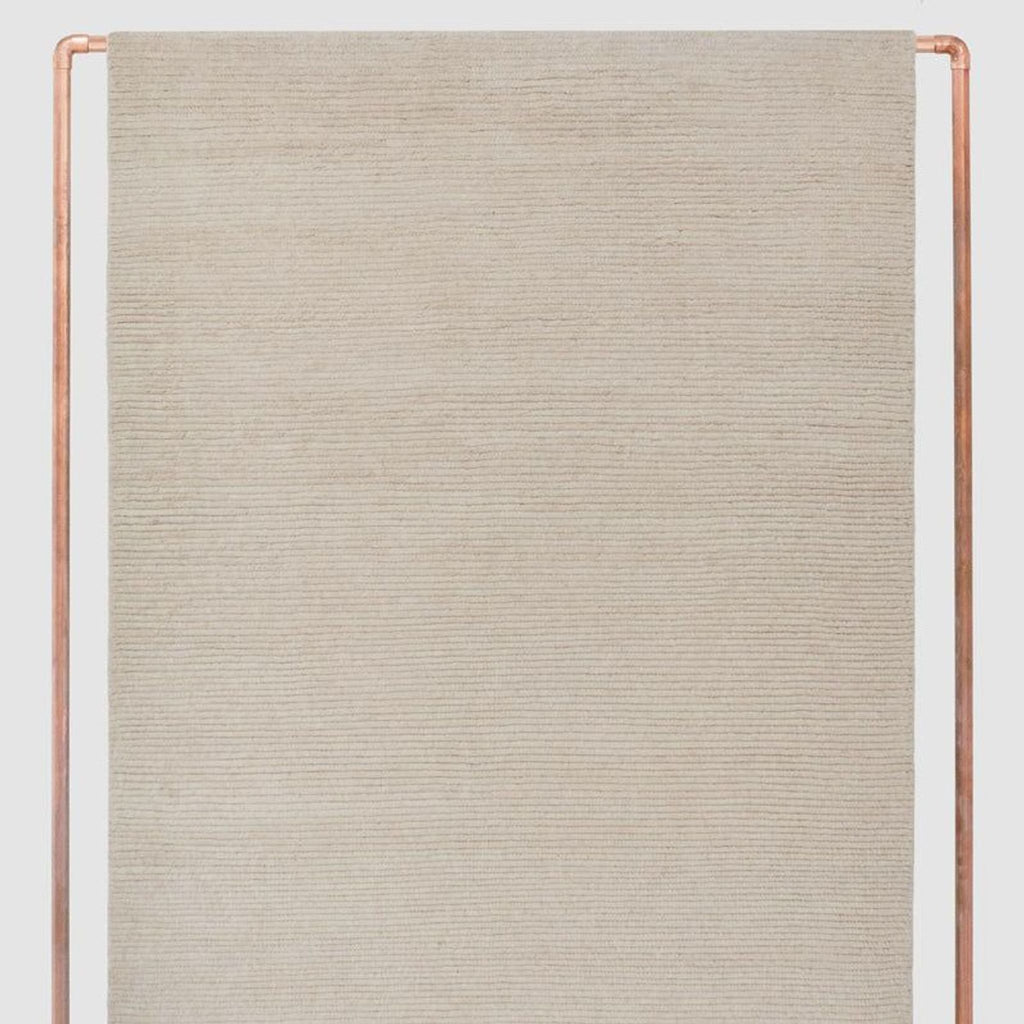 Handwoven natural wool rug by The Citizenry in a soft neutral color, featuring subtle fringed edges.