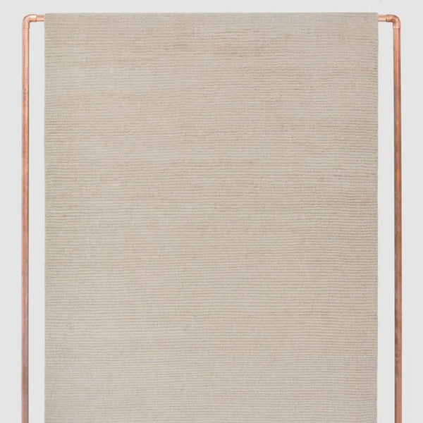 Handwoven natural wool rug by The Citizenry in a soft neutral color, featuring subtle fringed edges.