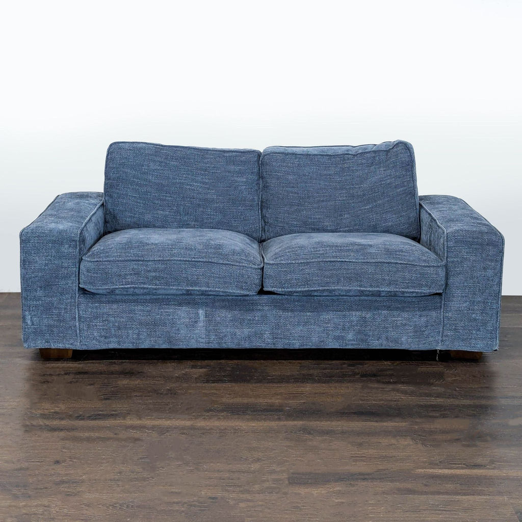 Modern blue 3-seat sofa with wide square arms and plush cushions in a contemporary living room setting.