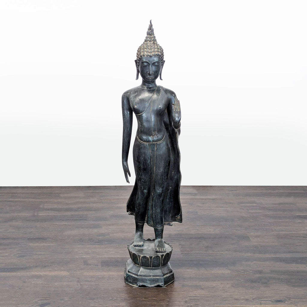 Bronze standing Buddha sculpture with raised hand, detailed robe, and ornate base, exuding calm and peace.
