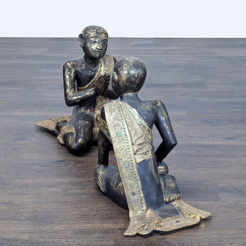 2. Pair of dark kneeling figures in detailed gold-trimmed attire, one with hands pressed together, facing each other.