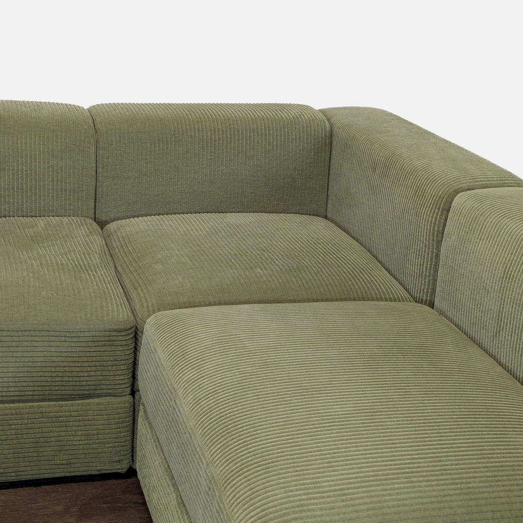 Modern green corduroy sectional by Ikea with under-seat storage, perfect for maximizing living room seating and space.