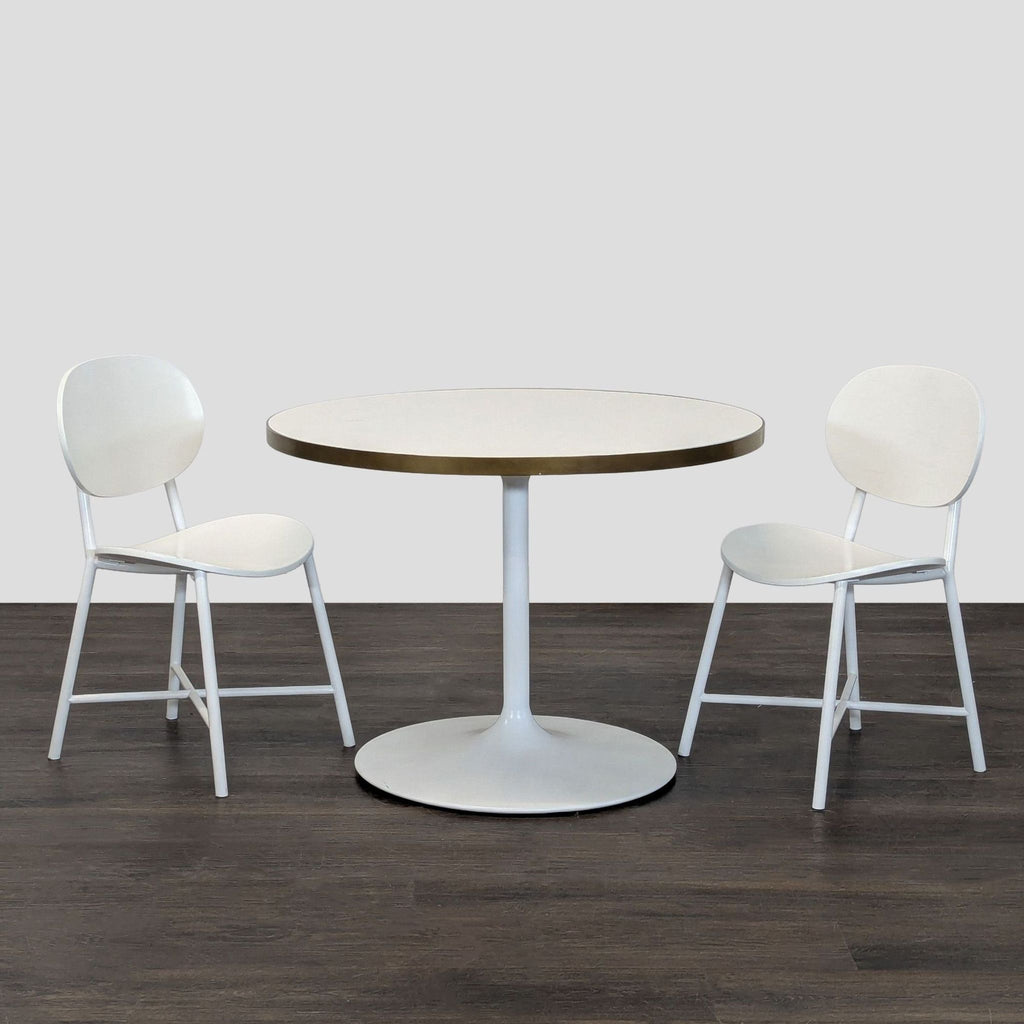 Modern white kids' dining set by RH Baby & Child, includes pedestal table and two chairs with gold accents.
