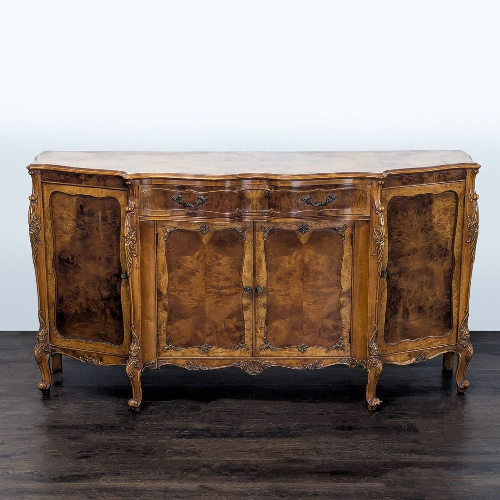 Serpentine-front sideboard with carved doors, a central drawer, and ornate burl inlay accents.  