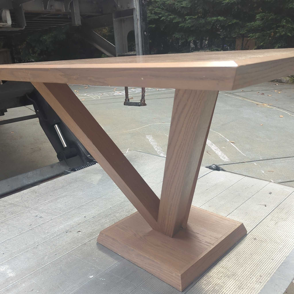 2. Side angle of a rectangular wooden dining table featuring a central V-shaped support and sturdy square base.