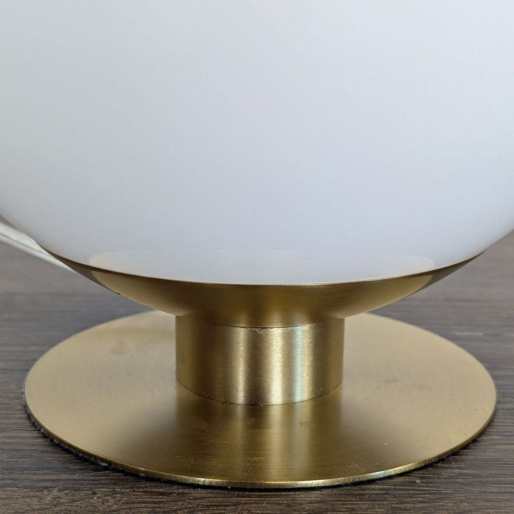 Stylish West Elm lighting: brass base, white globe lamp, emits soft glow for any modern space.