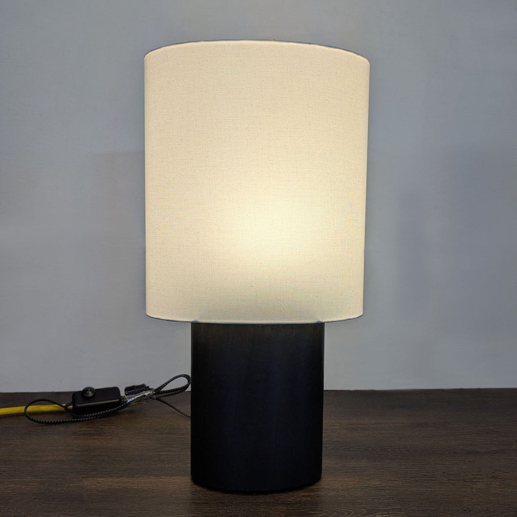 Room & Board lighting—sleek table lamp with black wood base and white shade; suits any modern space.
