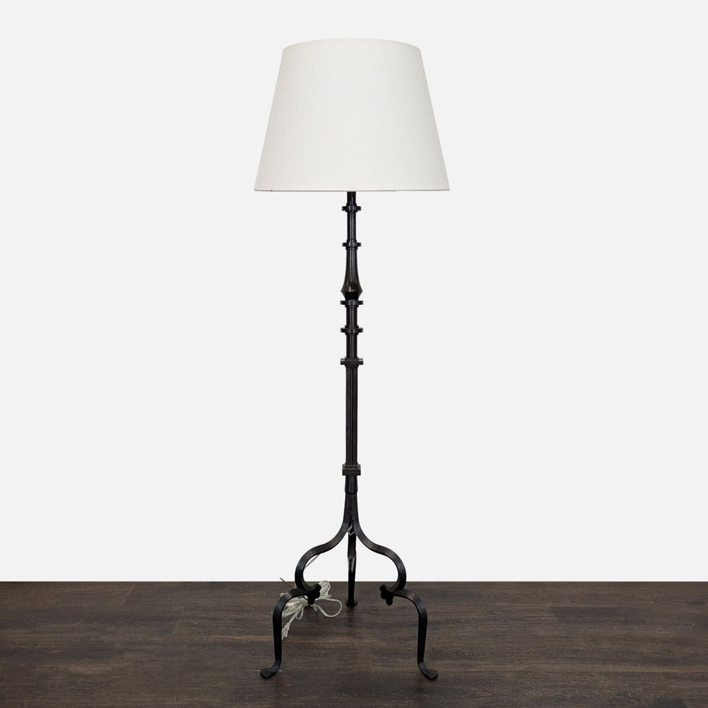 Black tripod floor lamp with a simple white shade, offering modern lighting for any room.