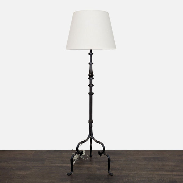 Black tripod floor lamp with a simple white shade, offering modern lighting for any room.