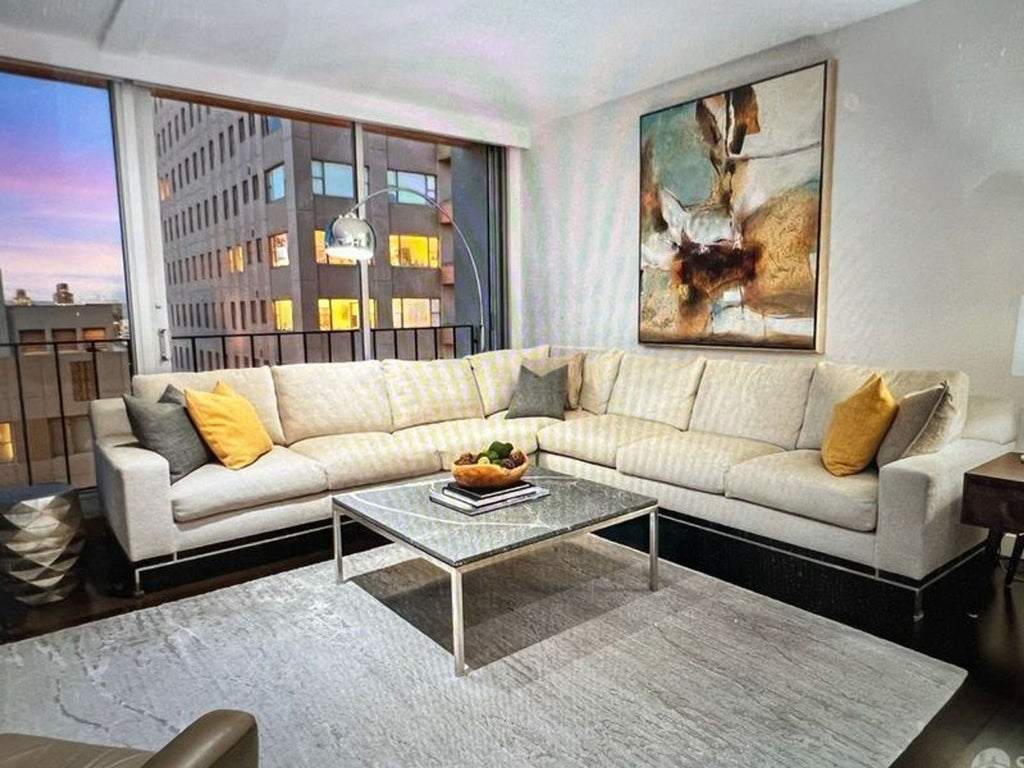 2. Contemporary living room with an A. Rudin sectional, yellow pillows, city view, abstract art, and large windows.