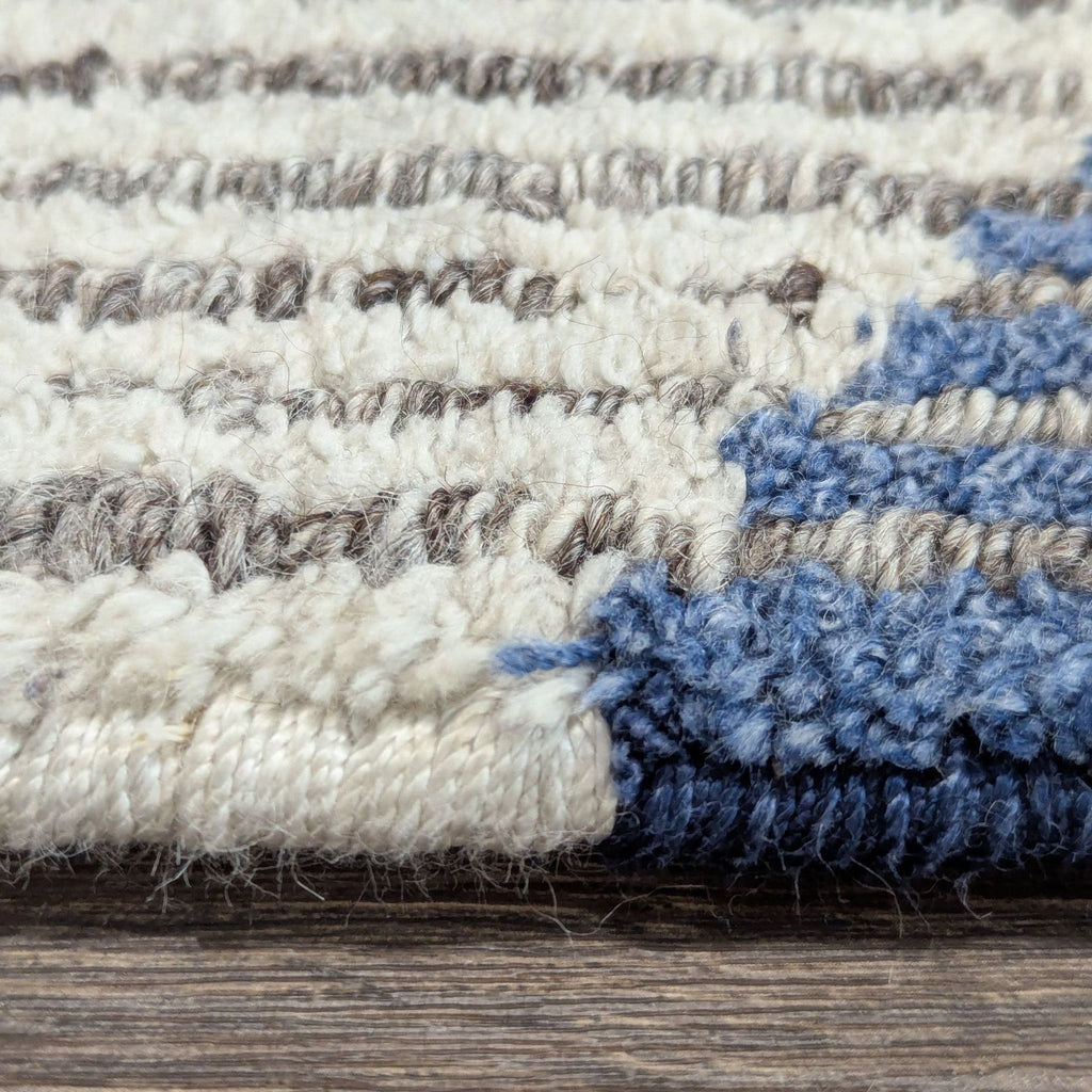 Kalaty brand wool rug in neutral and blue shades, featuring a low pile and contemporary abstract pattern.