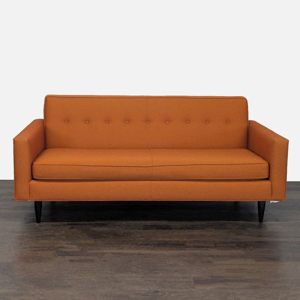 Burnt orange 3-seat sofa by Design Within Reach with button-tufted back and black legs, modern style.