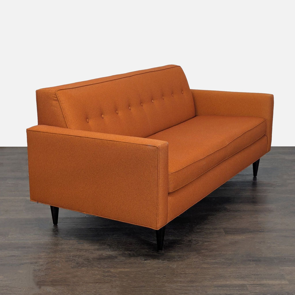 Contemporary Design Within Reach sofa for three, featuring boxy lines, warm orange fabric, and tufted back.