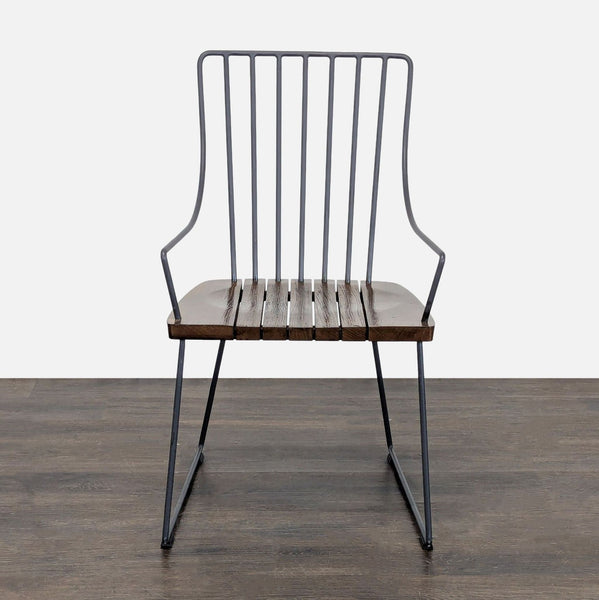 Modern black metal chair with slatted dark wood seat, open-back design, and armrests by Crate & Barrel.