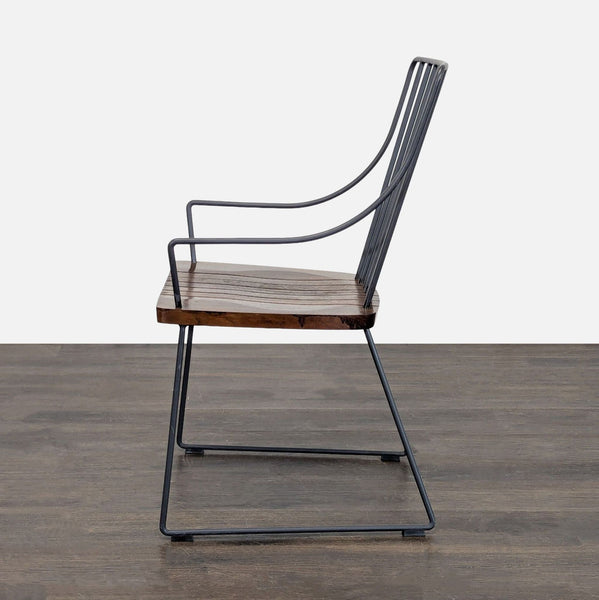 1. Side view of a Crate & Barrel chair with a metal frame and slatted wooden seat over a dark floor.