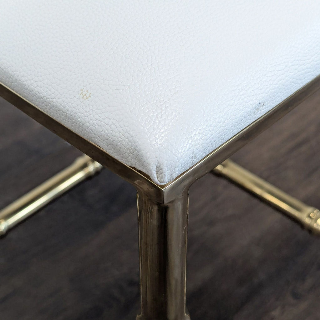 2. Close-up of brass frame corner and white cushion upholstery of a decorative stool.