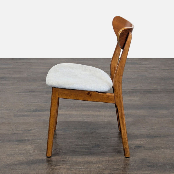 1. Side view of a West Elm dining chair with a curved wooden frame and light upholstered seat on dark flooring.