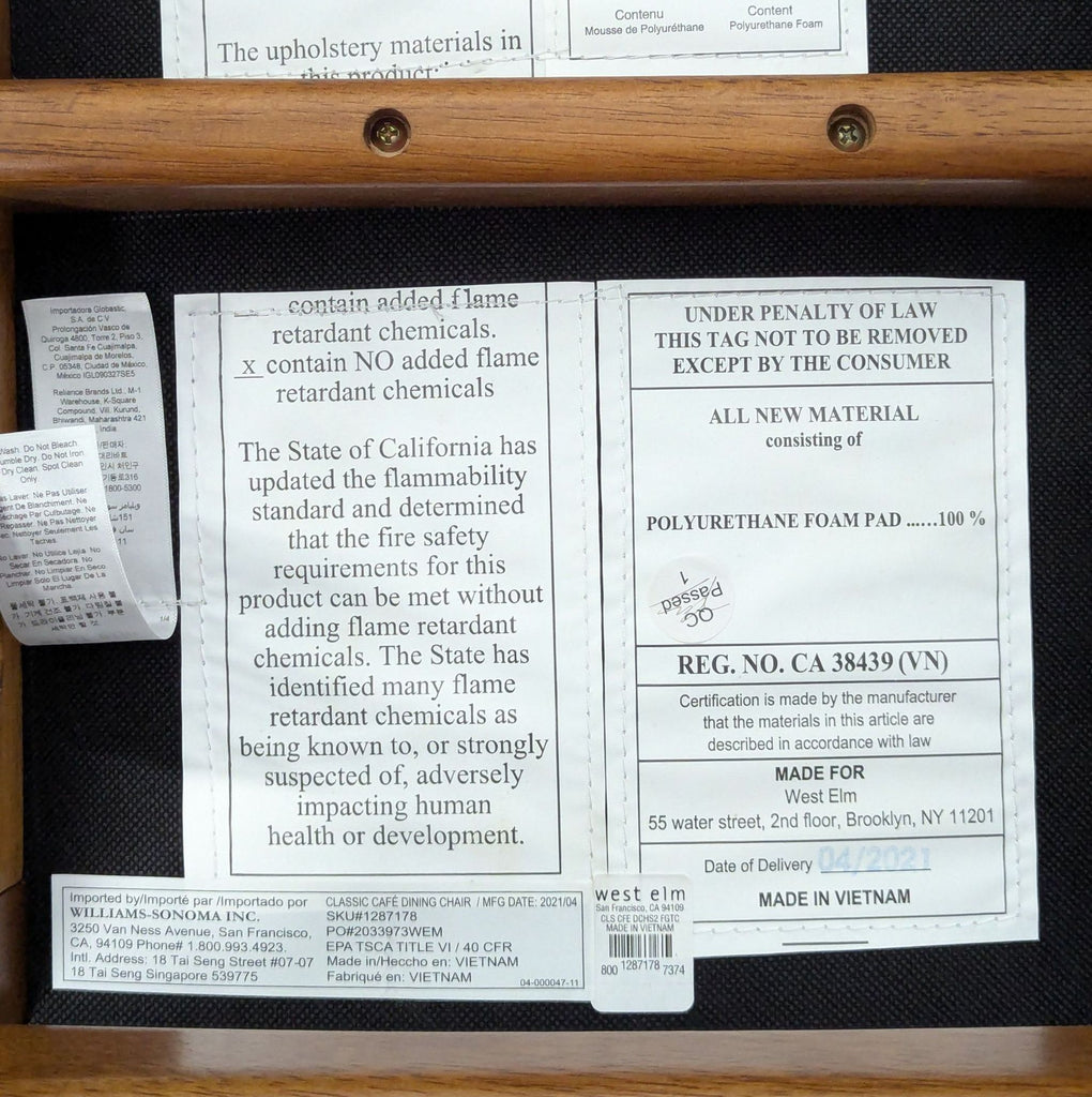 3. Manufacturer and safety label tags under a West Elm dining chair, showing materials and compliance information.