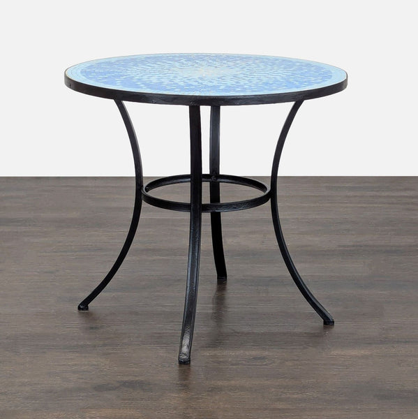 Blue mosaic round patio table from Crate & Barrel with black metal base, suitable for indoor or outdoor use.