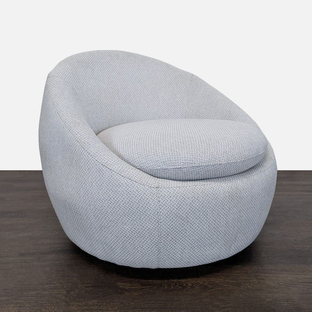 Contemporary lounge chair featuring soft, easy-to-clean grey upholstery and a spacious, circular seat.