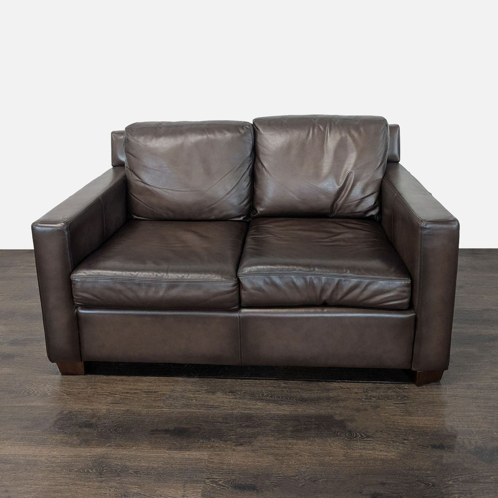 Brown leather Pottery Barn loveseat with plush cushions and a modern design, ideal for cozy spaces.