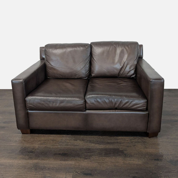 Brown leather Pottery Barn loveseat with plush cushions and a modern design, ideal for cozy spaces.
