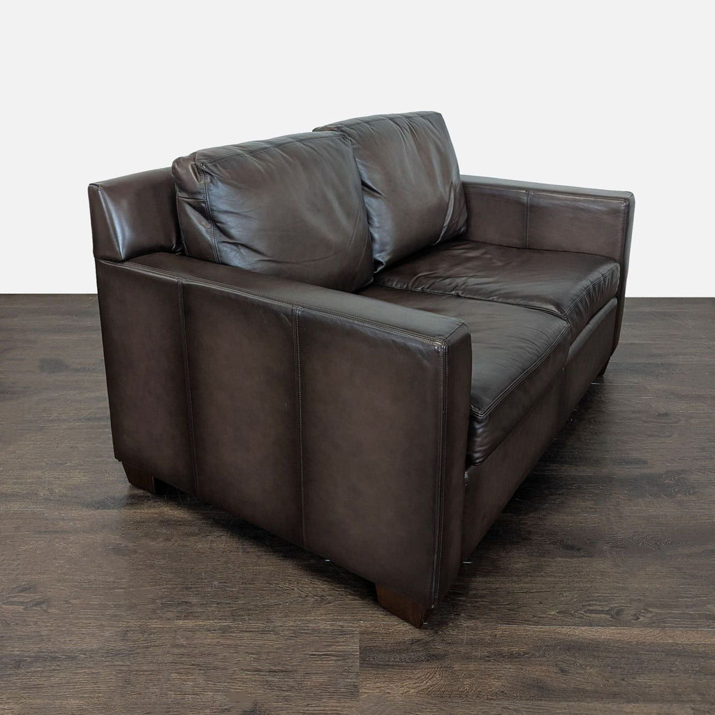 Contemporary Pottery Barn loveseat in rich brown leather, designed for comfort and style in small rooms.